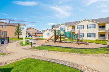 A playground with a slide and a green fence is surrounded by houses.
